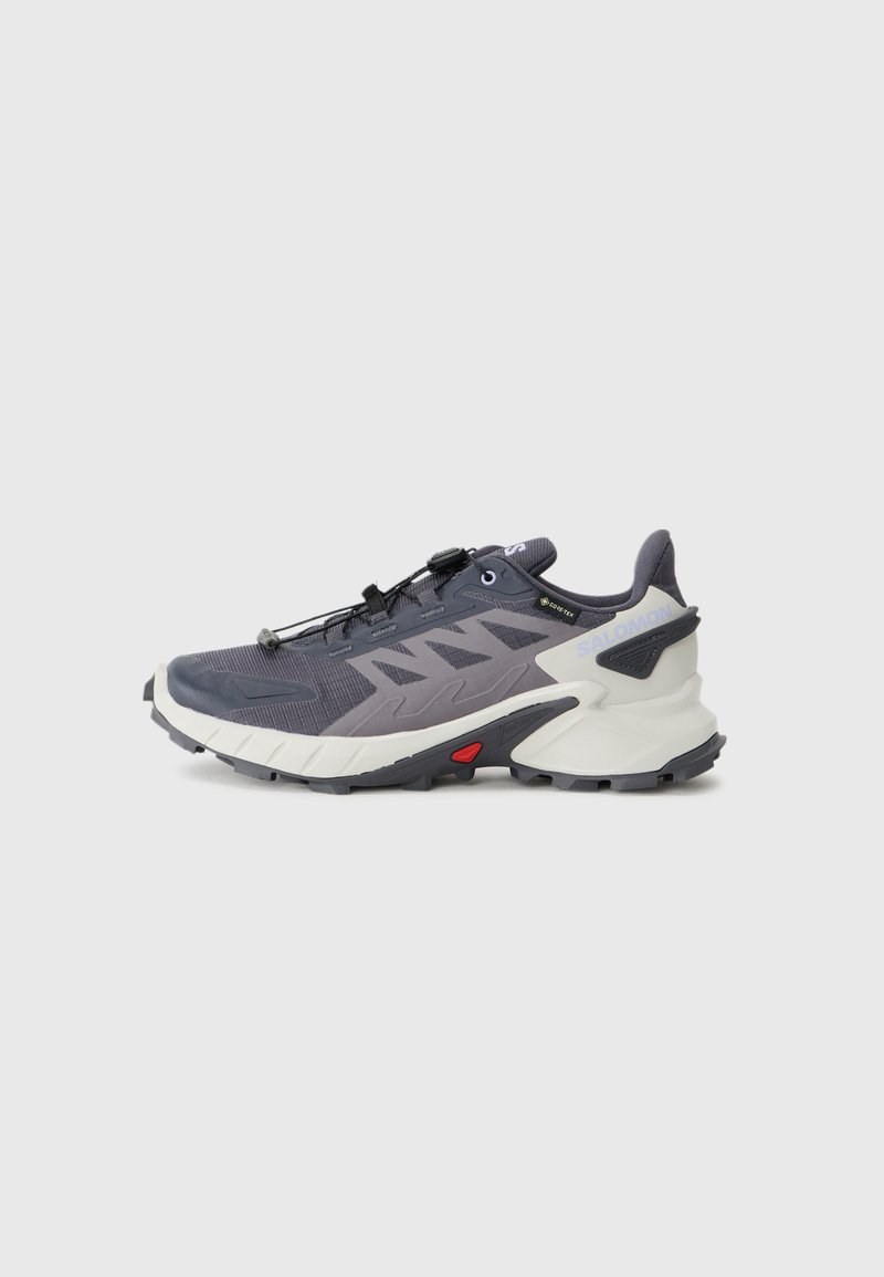 Pantofii sport gri și bleumarin au un material superior din plasă, talpă de protecție, talpă neagră și accente roșii. Dispune de un sistem rapid de șireturi și guler captusit.