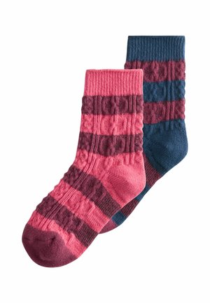Zwei Wollsocken, eine pink mit kastanienbraunen Streifen, die andere blau mit kastanienbraunen Streifen, beide mit einem Kabelstrickmuster.