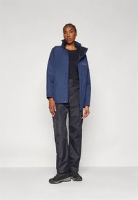 Tumesinist vettpidav jakk kapuutsiga, trukkide ja taskutega, sellega sobivad mustad vettpidavad püksid ja tugevad mustad jalanõud.