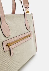 Sac fourre-tout beige texturé avec des accents roses, présentant une poche zippée à l'avant, des anses lisses et une forme structurée. Détails en métal doré visibles.