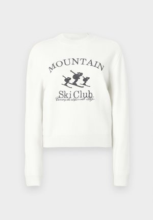 Valge lühike pusa, millel on ümar kaelus, pikad varrukad ja suusatajate graafiline trükk koos tekstiga "MOUNTAIN Ski Club".