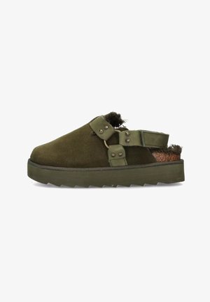 Zoccoli in suede verde con superficie texture, dotati di cinturini regolabili, dettagli in metallo e suola spessa per una maggiore aderenza e supporto.