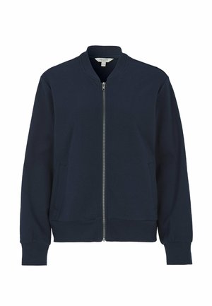 Laivastonsininen vetoketjulla varustettu takki, jossa on resoripintainen kangas, pystymallinen kaulus, sivutaskut ja pitkät hihat. Siinä on hopeanvärinen vetoketju.