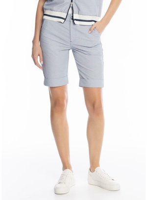 Osoba ubrana w jasnoszare podwinięte szorty, białe trampki oraz lekką kurtkę z zamkiem i granatowymi paskami.