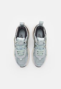 Paire de baskets Nike gris clair et blanc avec des détails en mesh et cuir, vues de dessus sur un fond uni.