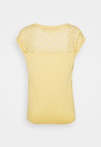 T-shirt jaune à manches courtes présentant un panneau en dentelle texturée sur le haut du dos, en matériau doux et avec une coupe décontractée.