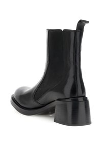 Botas Chelsea negras con parte superior de cuero brillante, paneles laterales elásticos y suela de tacón grueso. Textura suave con un diseño de punta redondeada.