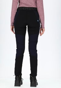 Schwarze Outdoor-Hosen mit engem Schnitt, ausgestattet mit einem breiten Bund mit "EDE MOUNTAIN"-Logo, akzentuiert durch dunkelblaue Einsätze und Reißverschluss-Taschen.