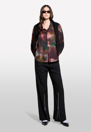 Camicia a maniche lunghe, con bottoni, in tessuto multicolore e traslucido; abbinata a pantaloni neri a vestibilità rilassata con cerniere alle caviglie.