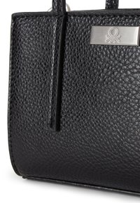 Černá kožená kabelka s texturou, která má kovovou značku a hladké hrany; obsahuje dvojité uchy pro všestranné nošení.