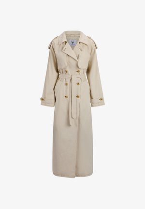 Beige lang trenchcoat med dobbeltradede knapper, midjebelte, skulderklaffer og mansjettstropper på ensfarget bakgrunn.