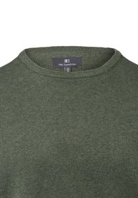 Olivgrüner Pullover mit Rundhalsausschnitt, aus strukturierter Strickware. Mit einem Etikett "Nils Sundström", Größe M, und einem Flaggenlogo.