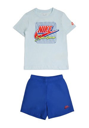 Maglietta Nike azzurro chiaro con logo rosso e giallo sopra pantaloncini sportivi blu con piccolo logo Nike rosso sulla gamba sinistra.
