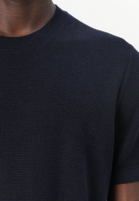 Mornarska majica s kratkimi rokavi in okroglim izrezom iz teksturirane rebraste tkanine. Kratki rokavi in eleganten izrez. Gladka površina z diskretnimi vzorčnimi detajli.