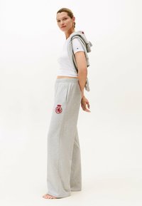 Grijze heather joggingbroek met een elastische tailleband, zijzakken en een rond rood embleem. Wit T-shirt met korte mouwen en een logo op de mouw.