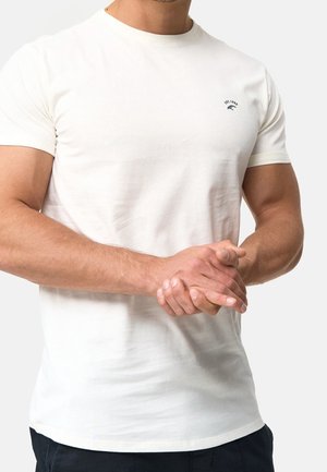 Biała koszulka z krótkim rękawem wykonana z bawełny, z małym czarnym logo na lewej piersi, prezentująca dopasowany krój i gładką teksturę.