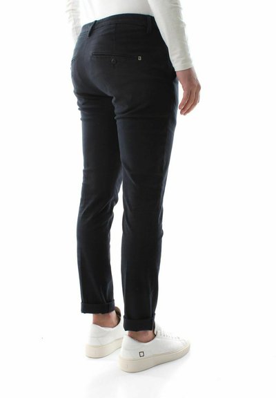 Slim-fit sorte bukser lavet af bomuldsblandinger, med baglommer der har lynlåse, manchetter i bunden, iført hvide sneaks.