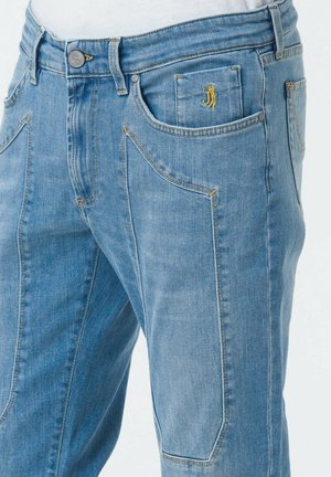 Jeans in denim blu chiaro con una vestibilità rilassata, caratterizzati da cuciture gialle, diverse tasche e un piccolo logo vicino alla tasca anteriore.