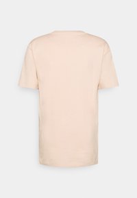 Kortermet t-skjorte i myk beige bomull, med rund hals, rett fasong, og uten mønstre eller grafikk på baksiden.