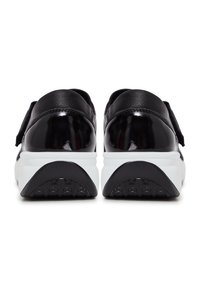 Baskets en cuir verni noir avec semelles blanches, présentant une texture lisse et une forme structurée. Une sangle Velcro en haut ajoute du détail.