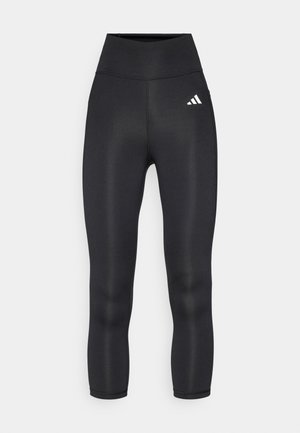 Mustade kõrge vöökohaga legginsid, millel on sujuv ja veniv materjal ning vasaku puusa peal väike valge Adidas'i logo.