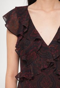 Sötét mintás ruha fodros ujjakkal, V-nyakkivágással és részletes paizsli mintával bordó, fekete és mély földszínekben.