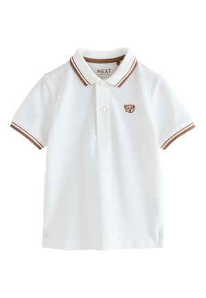 Valkoinen lyhythihainen poolopaita, jossa on ruskearaidallinen kaulus ja kalvosimet, kaksi nappia ja pieni nallekarhukirjailu rinnassa.