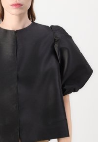 Schwarzes Satin-Croptop mit Rundhalsausschnitt, puffartigen Ärmeln und glatter Textur. Verfügt über einen Frontverschluss und ein minimalistisches Design.