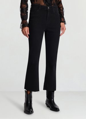 Jeans in denim nero con orlo svasato e bordi sfrangiati. Presentano una vita aderente e cuciture sottili. Abbinati a stivaletti neri alla caviglia.