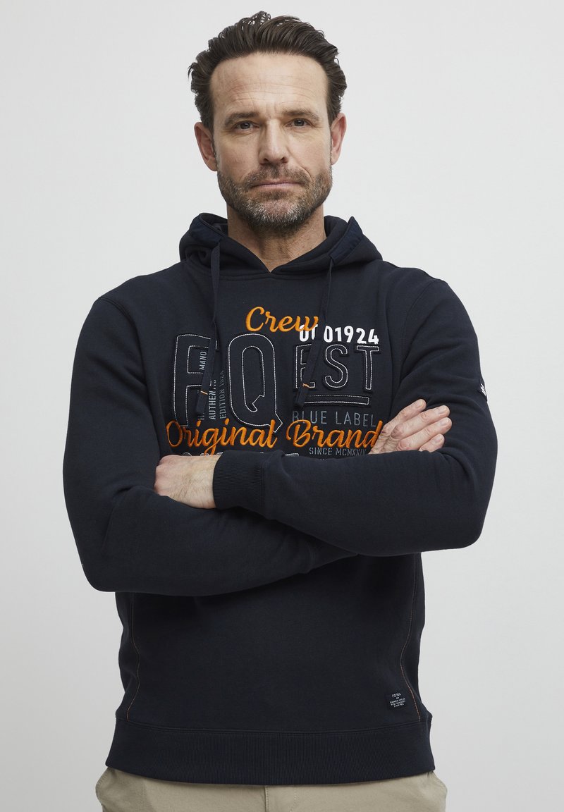Sudadera azul marino con capucha ajustable, texto gráfico frontal en blanco y naranja, puños acanalados y diseño de bolsillo canguro.