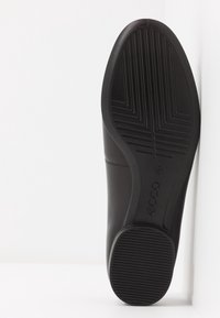 Semelle de chaussure en cuir noir avec motif texturé et logo ECCO embossé sur le dessous, sur fond blanc.