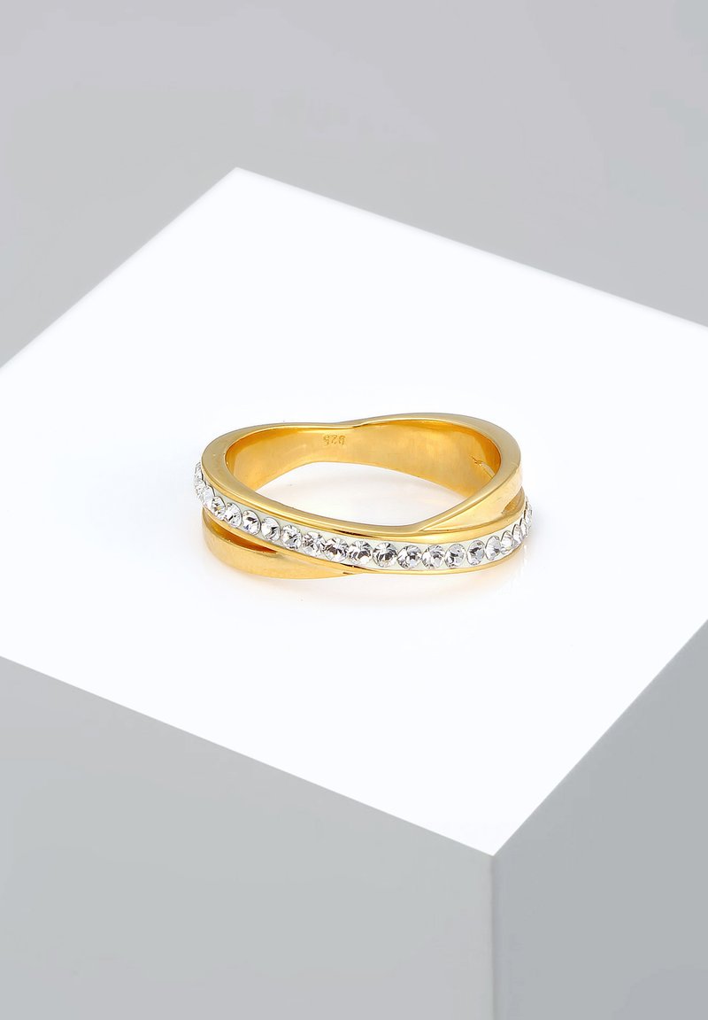 Anillo de oro con un diseño entrelazado, la banda está acentuada por piedras transparentes, con una textura suave y un acabado pulido.