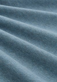 Denimstoff in Hellblau, mit diagonalen Falten und einer weichen Textur, mit feinen Farbvariationen und einer gewebten Oberfläche.