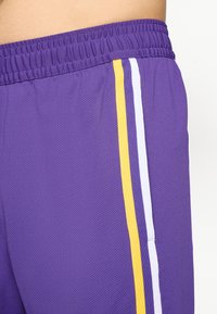 Lilla atletiske shorts med et struktureret stof, der har gule og hvide sidelister og en elastisk talje for komfort.