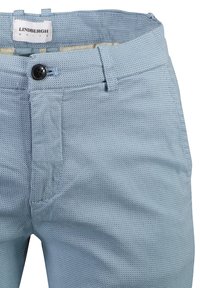 Ljust blå strukturerade byxor med knappstängning, två sidfickor och etikett i midjan. Materialet verkar vara andningsbart och mönstrat.