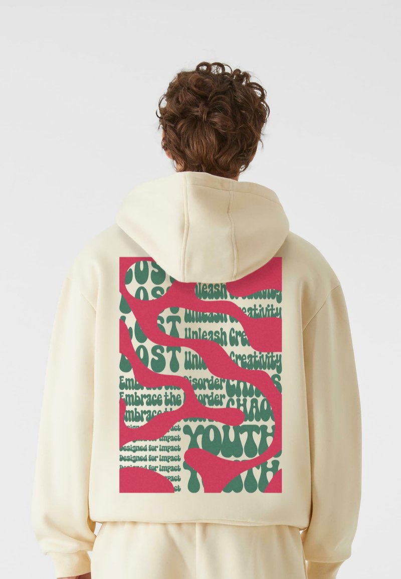 Hætte sweatshirt i blød beige stof. Store grafik på ryggen prydes af grønne og pink tekster med forskellige sætninger i fede, legende skrifttyper.