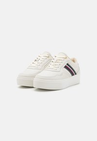 Hvite lær sneakers har en plattformsåle, dekorative stripete aksenter i rødt og blått, og gulløyer til skolisser.