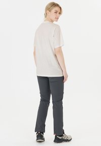 Ljusgrå kortärmad t-shirt i kombination med mörkgrå byxor, som har en slim fit och raka ben. Skorna är svarta och grå vandringsskor.