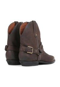 Botas de tobillo de cuero marrón con detalle de hebilla, cierre de cremallera y acentos cosidos. Superficie texturizada y tacón bajo apilado.