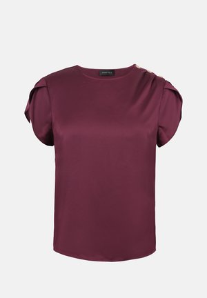 Blusa in satin bordeaux con maniche corte a sbuffo e tre bottoni decorativi sulla spalla sinistra, scollo rotondo, finitura liscia.