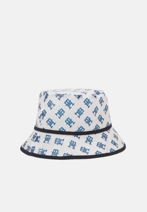 Biały kapelusz typu bucket z niebieskim powtarzającym się wzorem geometrycznego logo oraz czarną lamówką wokół rond i korony.