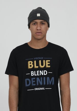 Black t-shirt featuring yellow, white, and blue text: "VINTAGE BLUE BLEND DENIM ORIGINAL." Gray beanie with a logo patch.