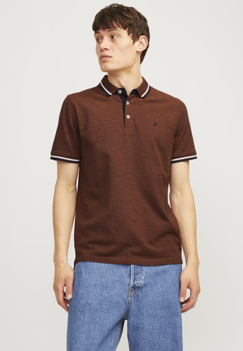 Bruine polo met een gestructureerde brei, voorzien van een marineblauwe kraag en manchetten met witte strepen. Twee knoopsluiting en klein logo detail.