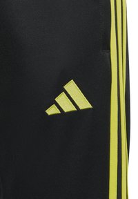 Zwarte sportshorts met gele strepen en een geborduurd geel Adidas-logo. Gemaakt van textuurstof, met een zijzak.