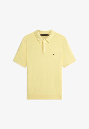 Gelbes Poloshirt mit kurzen Ärmeln, drei weißen Knöpfen und einem kleinen Tommy Hilfiger-Logo auf der linken Brust.