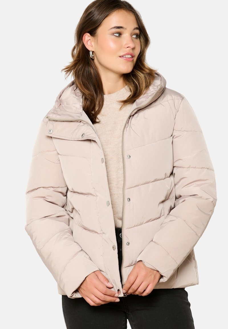 Veste matelassée beige avec capuche, présentant un design à panneaux horizontaux, des boutons-pression et une fermeture à glissière à l'avant. Matériau doux et isolant.