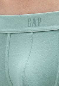 Μποξεράκια σε μέντα πράσινο με απαλή υφή. Η μέση έχει το λογότυπο "GAP" σε πιο σκούρο χρώμα. Απλός σχεδιασμός χωρίς σχέδια.