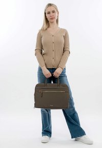 Brown, textured laptop bag with a front zip pocket, dual top handles, and a sleek, rectangular design, held by a person in casual attire.
