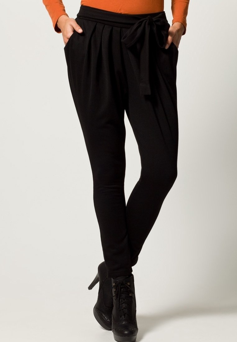 Pantalon noir à taille haute, doté de plis et d'une ceinture à nouer. Tissu lisse et silhouette ajustée se rétrécissant à la cheville.