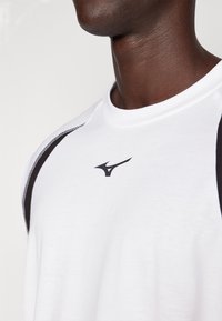 Valge spordipäevik mustade aksentide ja musta logoga rinnal. Valmistatud kergest riidest, millel on sile tekstuur.